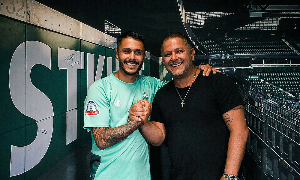 Leonardo Bittencourt und sein Vater Franklin vor einem Bild der Ostkurve im wohninvest WESERSTADION.