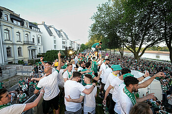 null Die Spieler stehen auf dem Truck, unten laufen die Fans.