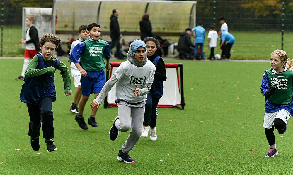 Eine Gruppe von Kindern rennt auf einem Fußballlfeld