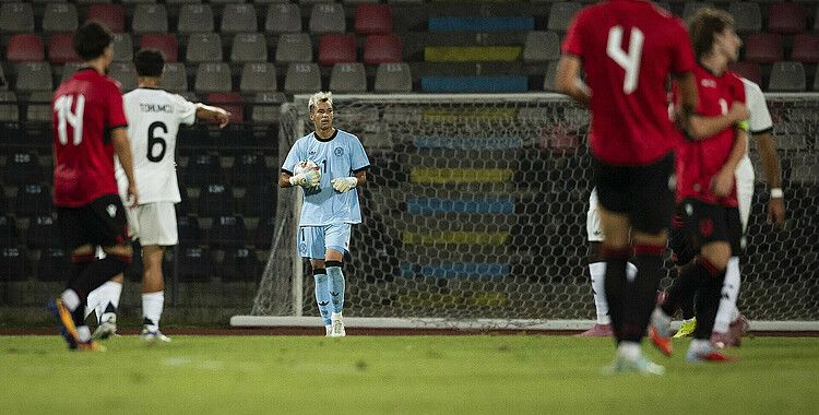 Fußballspielszene mit Mio Backhaus im blauen Torwarttrikot des DFB. Er hält den Ball, umgeben von Spielern in roten (albanischen Spielern) und weißen Trikots (Mitspieler der deutschen Nationalmannschaft) auf dem Spielfeld.