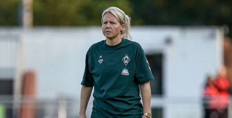 Fritzy Kromp steht mit einem grünen Werder-Tshirt im Freien und blickt mit konzentriertem Gesichtsausdruck nach vorne.