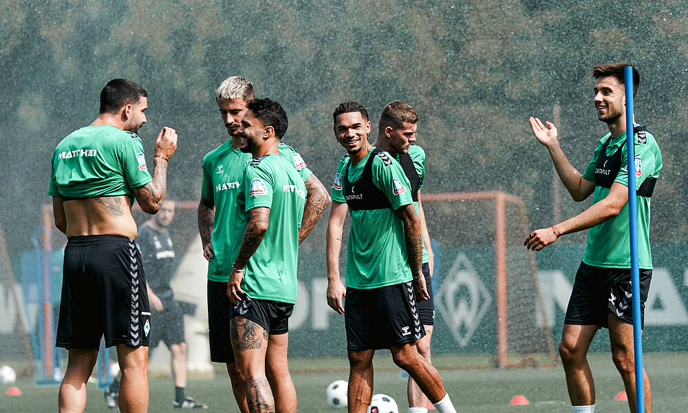 Die Werder-Profis stehen zusammen und lachen.