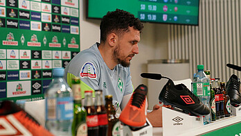 null Milos Veljkovic sitzt im PK-Raum am Mikrofon.