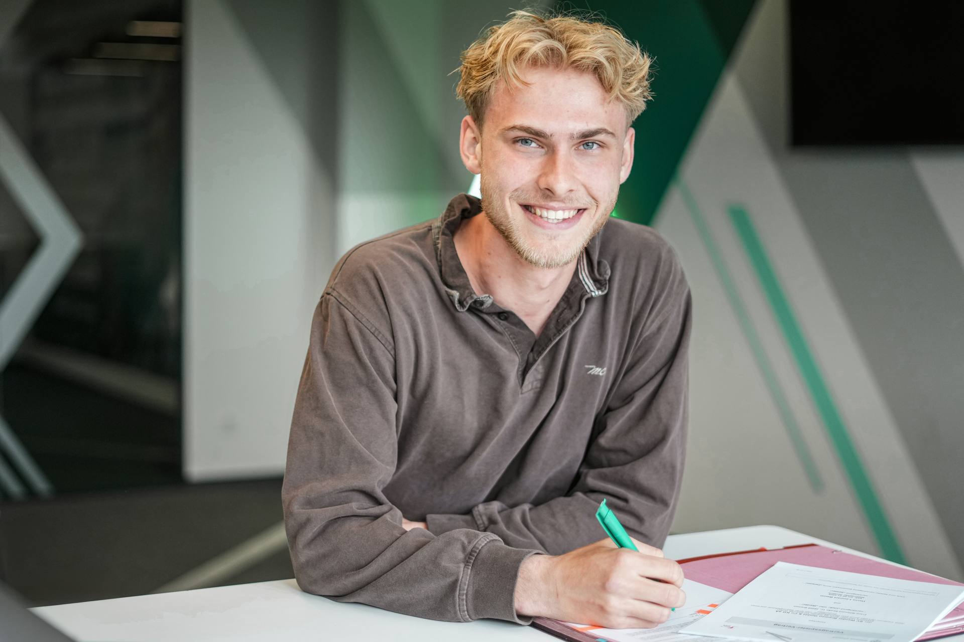 Lennart Baum sitzt an einem Tisch und unterschreibt einen Vertrag.