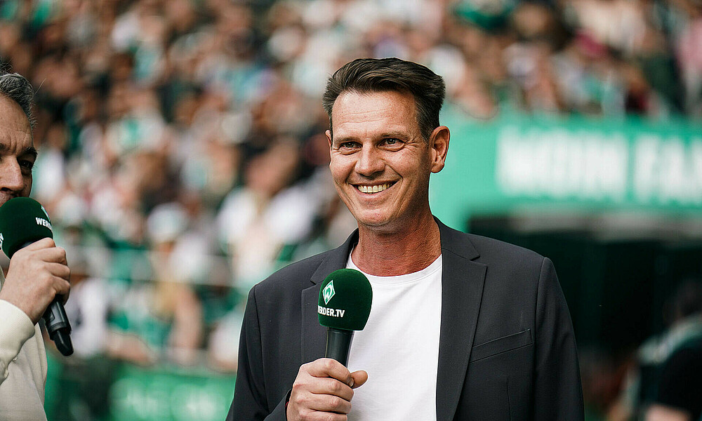 Tim Borowski am Mikrofon am Seitenrand. 