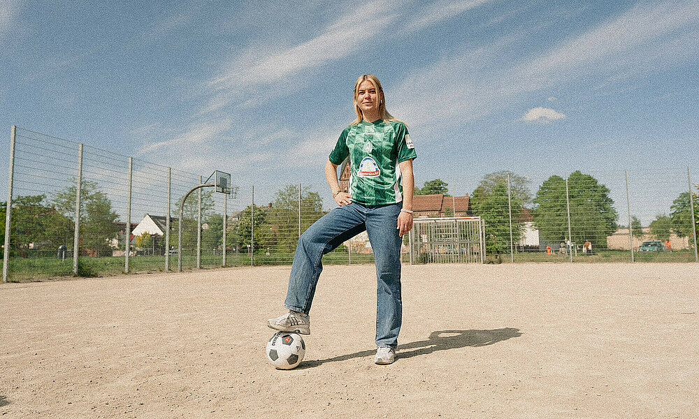 null Juliane Wirtz steht auf einem Bolzplatz. einen Fuß hat sie auf einem schwarz-weißen Ball.