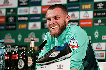 Marvin Ducksch Mixed-Zone Marvin Ducksch sitzt auf dem Podium der Pressekonferenz und lacht.