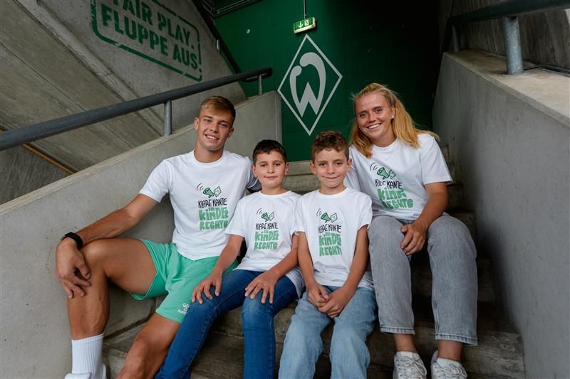 Keke Topp und zwei Kinder mit Ricarda Walkling im weißen T-Shirt mit der Aufschrift "Klare Kante für Kinderrechte"