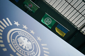 DFB Ukraine Die Flagge der Ukraine neben der DFB-Flagge hoch oben im Stadion aufgehängt. Im Vordergrund das DFB-Logo im Stadion auf einer Bande.