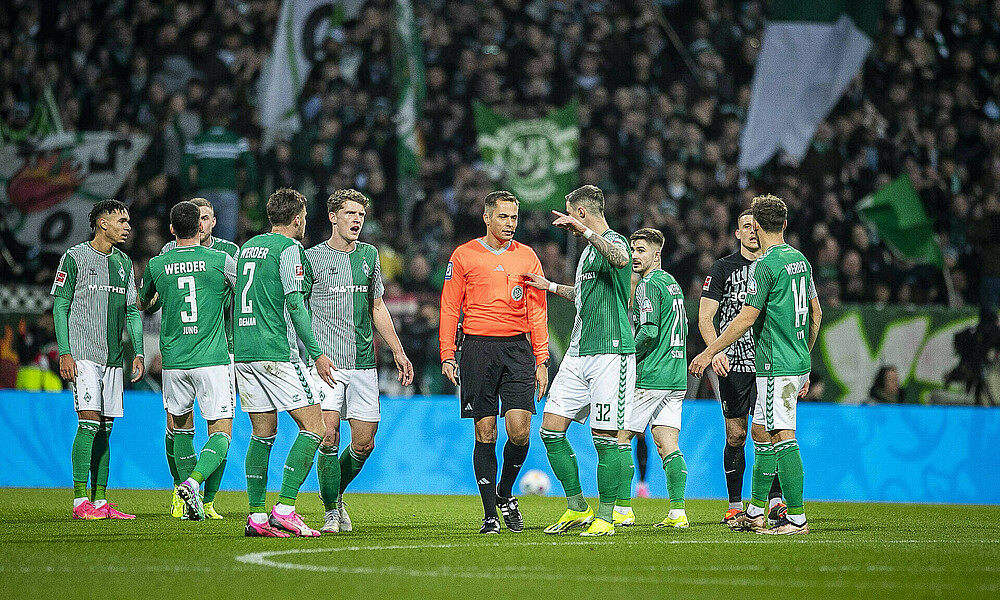 Die Werder-Spieler umzingeln Schiedsrichter Hartmann. 