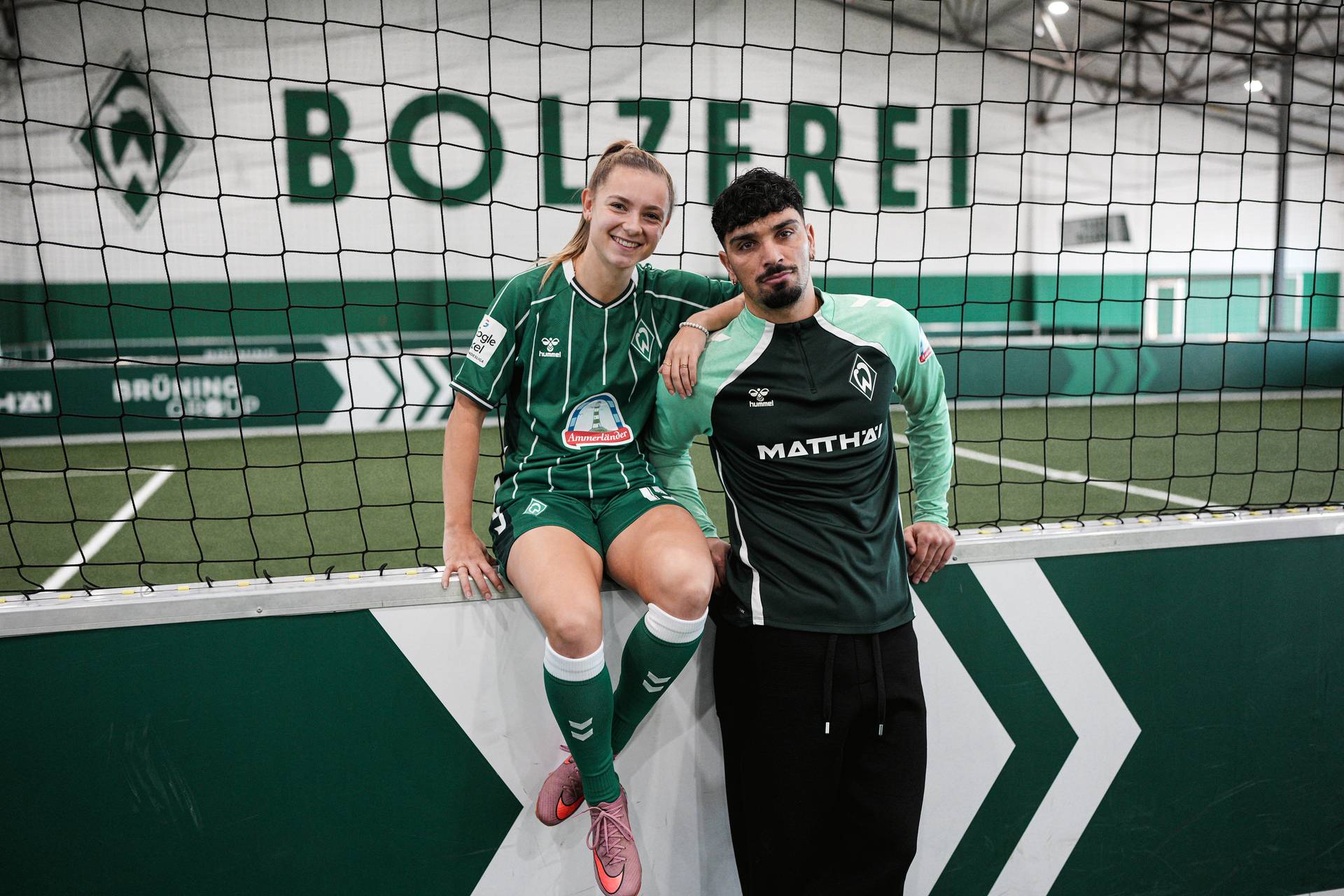 Michelle Weiß und Cameron Puertas stehen in der Bolzerei und lächeln in die Kamera.