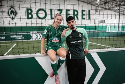 Michelle Weiß und Cameron Puertas stehen in der Bolzerei und lächeln in die Kamera.