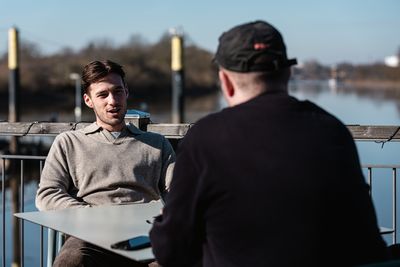 Olivier Deman sitzt im Interview an einem Tisch, im Hintergrund die Weser.