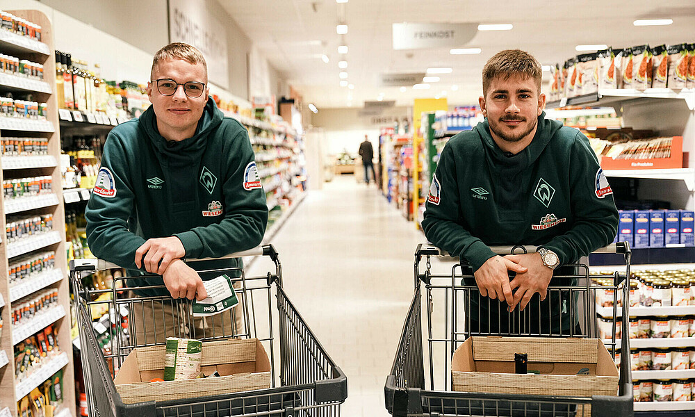 Niklas Schmid und Romano Schmid stehen jeweils an einem Einkaufswagen