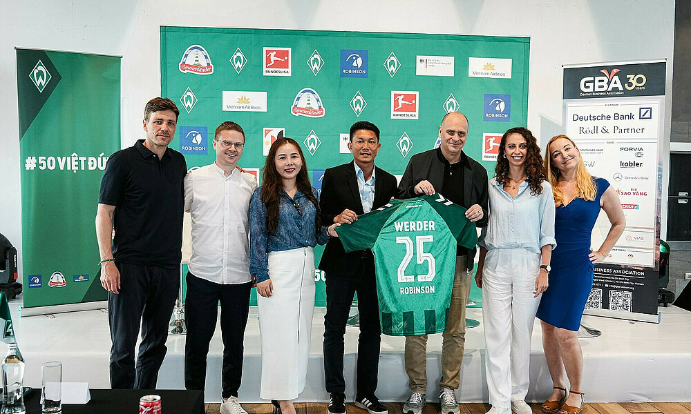 Gruppenfoto, bei dem Werders Vorsitzender der Geschäftsführung, Klaus Filbry, eine Trikot mit dem Flock 