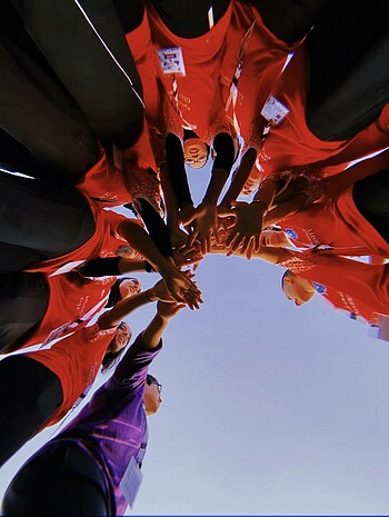 Frauengruppe steht im Kreis, die Hände in der Mitte