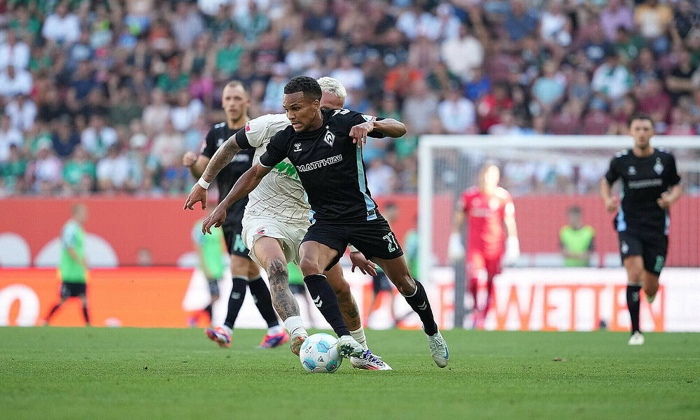 Felix Agu dribbelt an einem Augsburger vorbei.