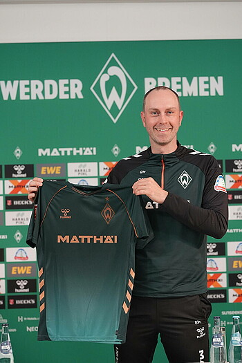 Cheftrainer Ole Werner hält das Third Trikot der neuen Saison 2025/26 in die Kamera