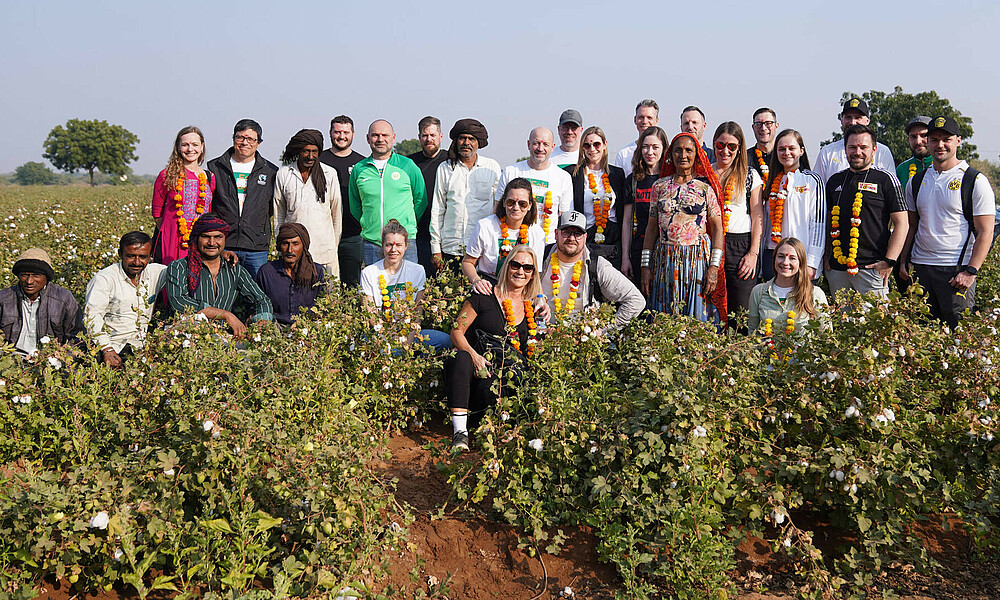 Gruppenfoto auf dem Baumwollfeld - die Teilnehmer:innen stehen zusammen.