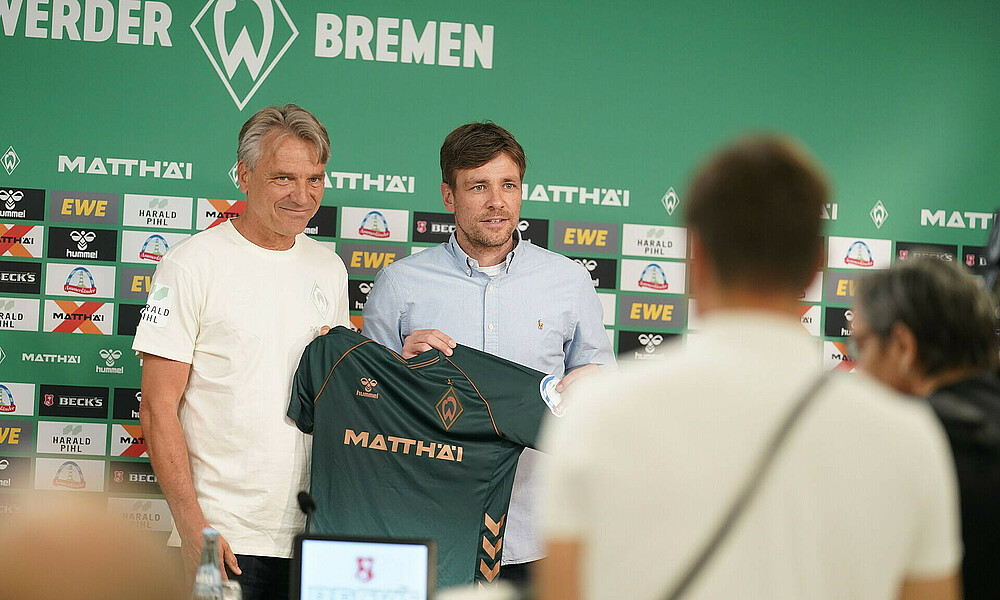 Horst Steffen hält mit Clemens Fritz ein Trikot hoch.