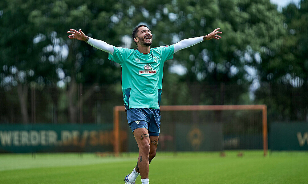 Leonardo Bittencourt lachend mit ausgebreiteten Armen auf dem Trainingsplatz.
