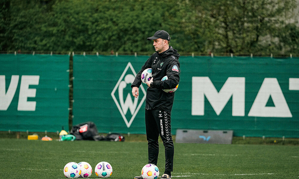 Ole Werner mit Bällen in der Hand auf dem Trainingsplatz. 