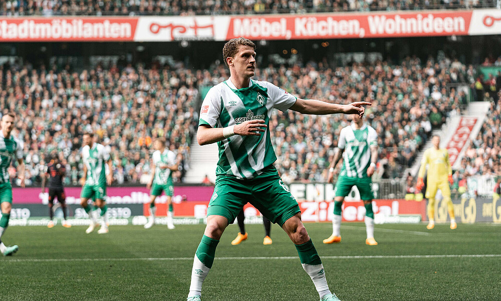 null Jens Stage deutet auf etwas, er steht dabei im Werder-Trikot auf dem Platz.