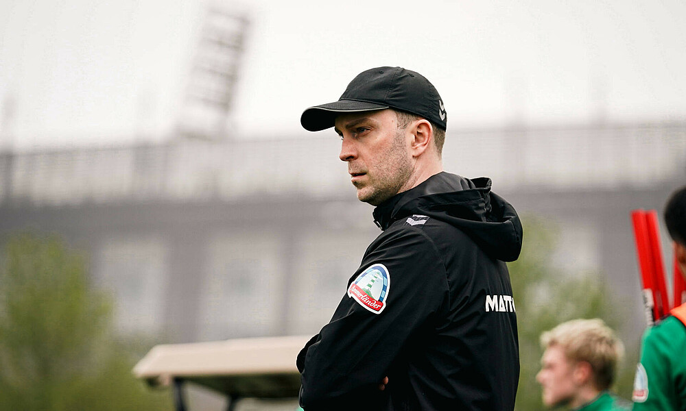 Ole Werner im Profil, steht mit verschränkten Armen auf dem Trainingsplatz.