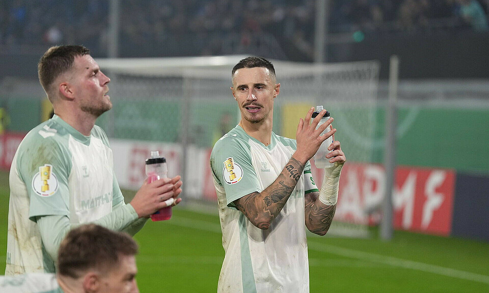 Marco Friedl klatscht in die Hände und schaut auf Nebenmann Marvin Ducksch nach dem Weiterkommen im Pokal gegen den SC Paderborn.