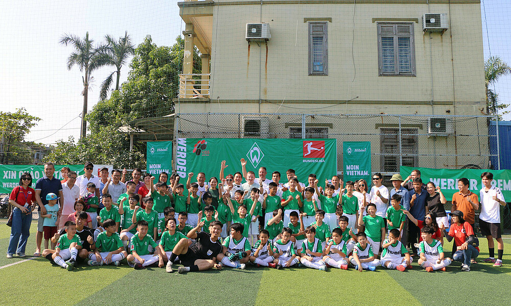 Viele Menschen stehen auf einem Fußballplatz zusammen.