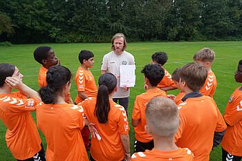 Ein Trainer versammelt seine Mannschaft um sich, um die Taktik zu besprechen. (Werder.de)