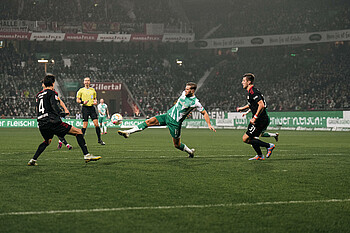 Niclas Füllkrug streckt das rechte Bein aus, um vor seinem Gegenspieler am Ball zu sein.