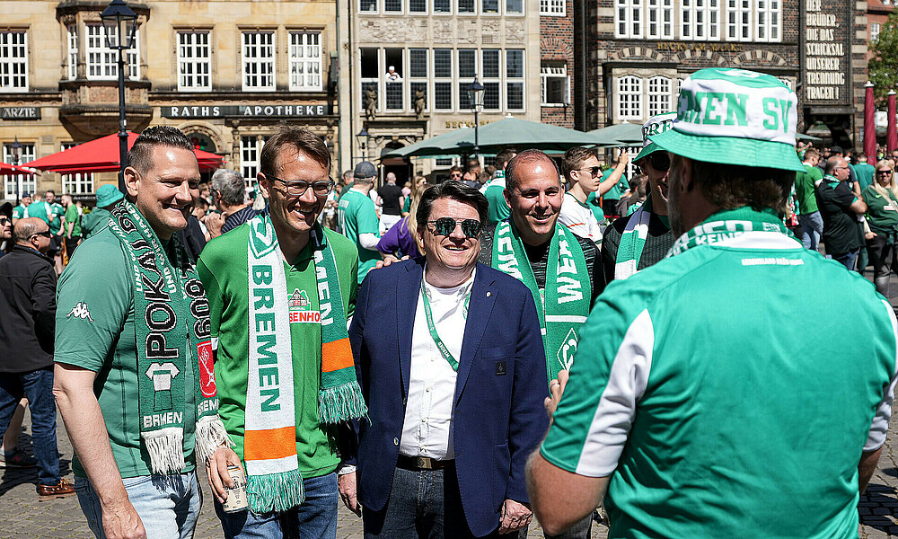 Dr. Hubertus Hess-Grunewald auf dem Marktplatz mit zwei Werderfans.