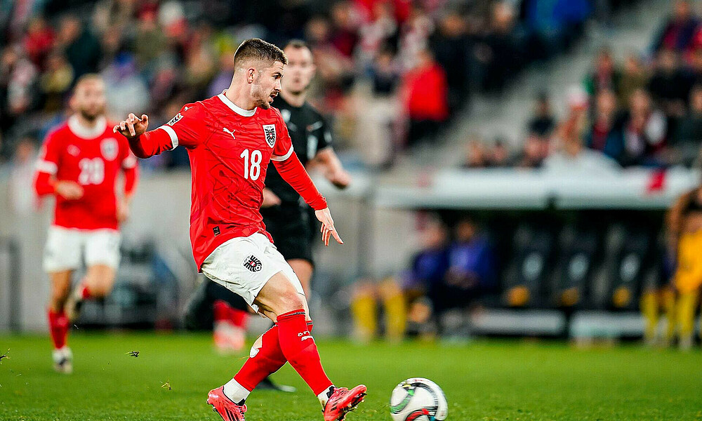 Romano Schmid spielt einen Pass und trägt dabei das Trikot Österreichs. 