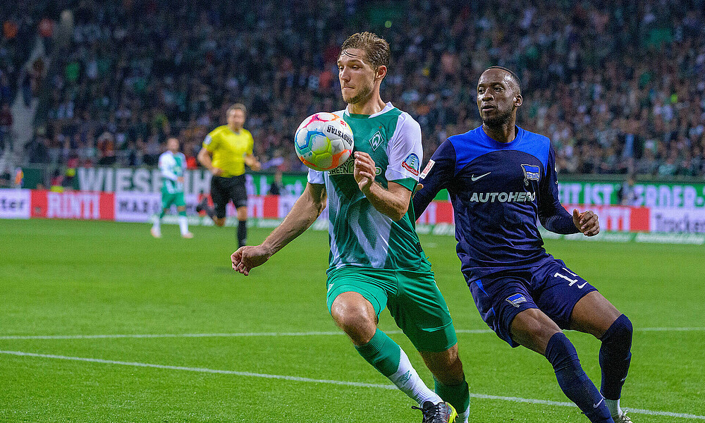 Niklas Stark nimmt den Ball während des Spiels mit der Brust an, hinter ihm läuft Dodi Lukebakio.