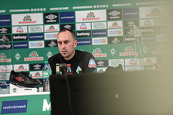 null Ole Werner sitzt auf dem Podium im PK-Raum.