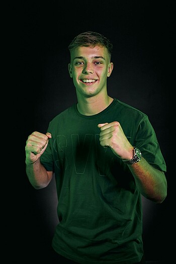 null Keke Topp ballt die Fäuste. Er steht vor dunklem Grund.