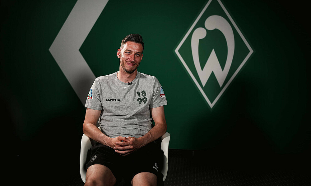 null Jiri Pavlenka auf einem Stuhl im Interview in einem grauen T-Shirt.