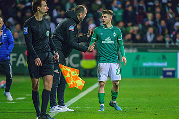 Ole Werner steht an der Seitenlinie zu Romano Schmid gebeugt und gibt ihm Anweisungen.