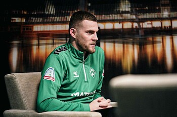 Marvin Ducksch sitzt in einem Sessel, die Hände zusammengefaltet. 