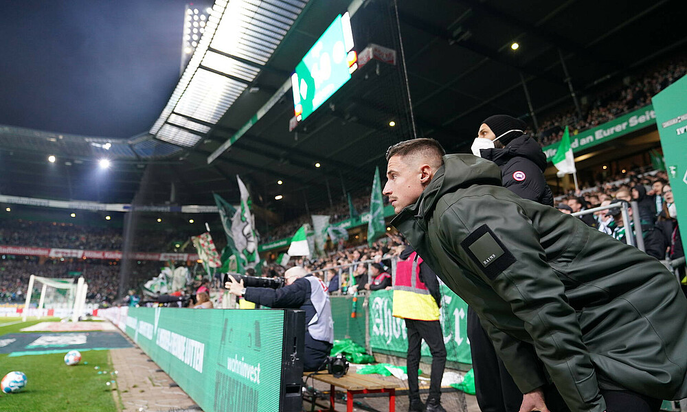 null Marco Friedl steht nach vorne gebeugt, hinter ihm Ömer Toprak. Beide stehen vor der Ostkurve.
