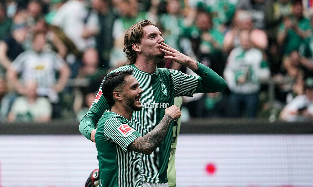 Leonardo Bittencourt und Nick Woltemade stehen Arm in Arm. Bittencourt ballt die Faust, Woltemade gibt einen Handkuss.