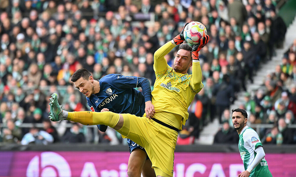 null Jiri Pavlenka fängt den Ball in der Luft, ein Bochum-Spieler versucht zum Kopfball zu kommen.r