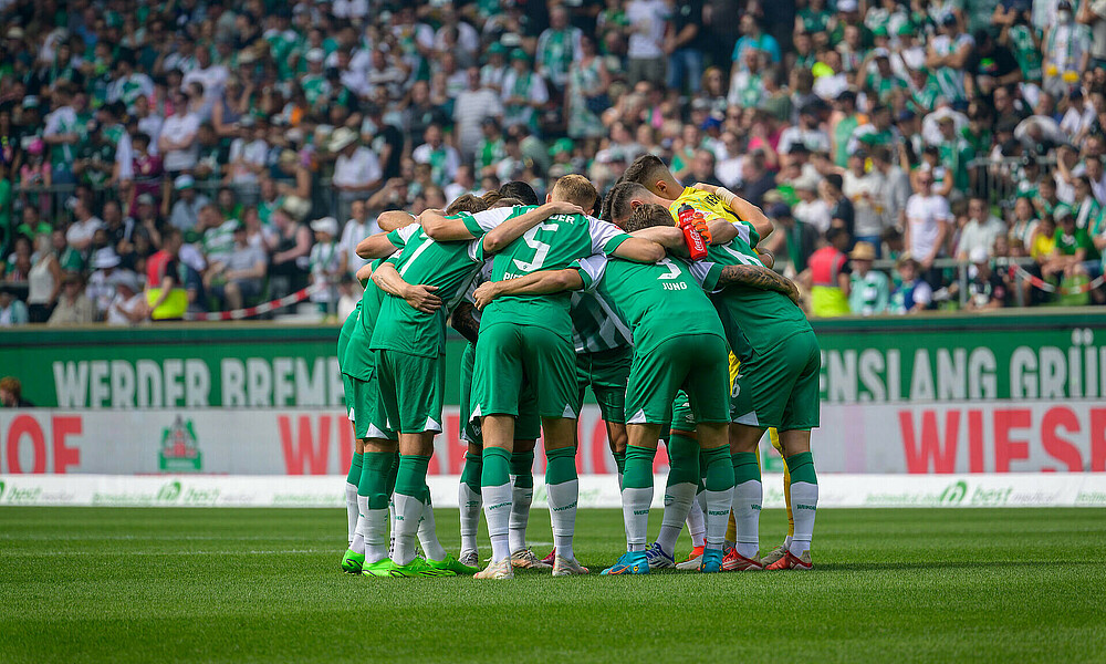 null Die Mannschaft steht eng im Kreis auf dem Feld zusammen.