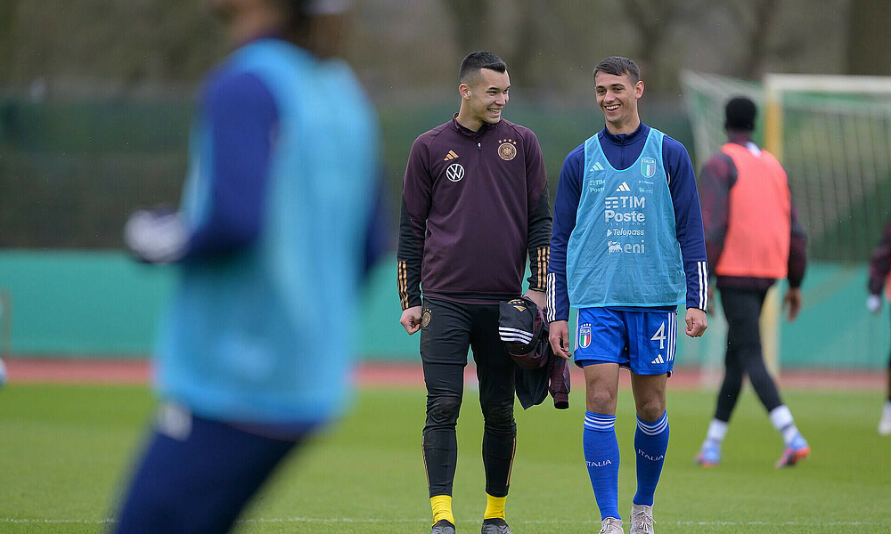 Fabio Chiarodia und Mio Backhaus lächeln gemeinsam auf dem Platz. 