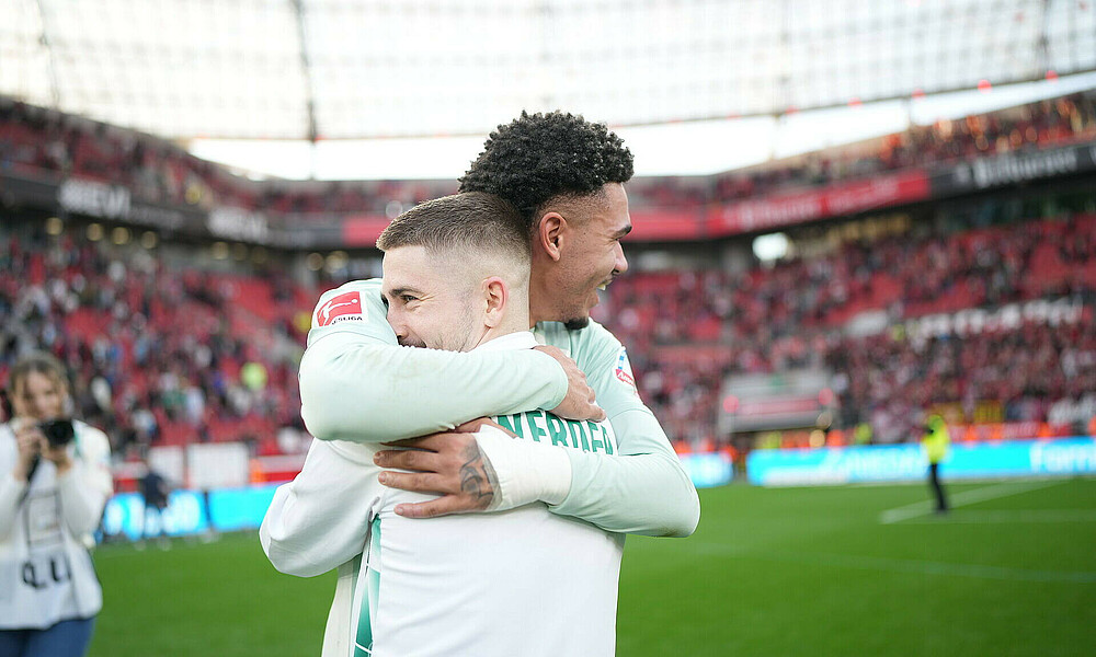 Romano Schmid und Justin Njinmah umarmen sich nach dem Sieg bei Bayer Leverkusen