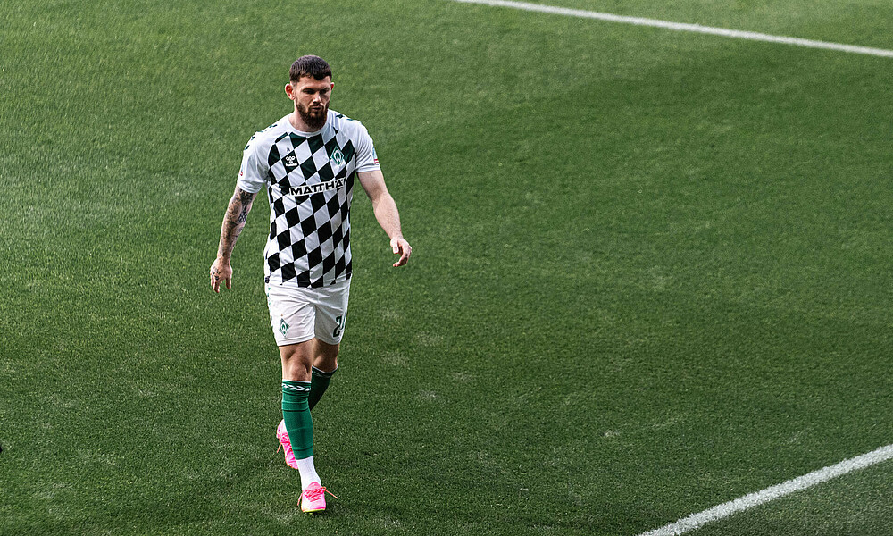 Oliver Burke verlässt das Spielfeld im karierten Aufwärmshirt.