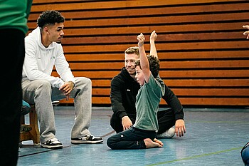 Justin Njinmah & Mitchell Weiser spielen mit einem Kind (Foto: Werder.de)