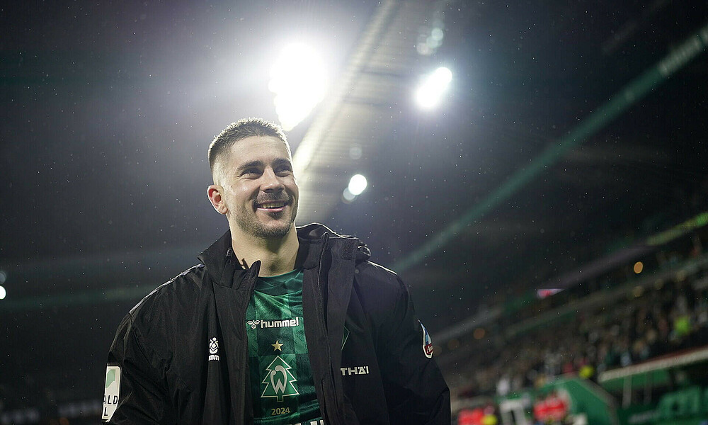 Romano Schmid schaut nach oben. Er ist im Weserstadion. Der Himmel ist dunkel. Das Flutlicht ist an.