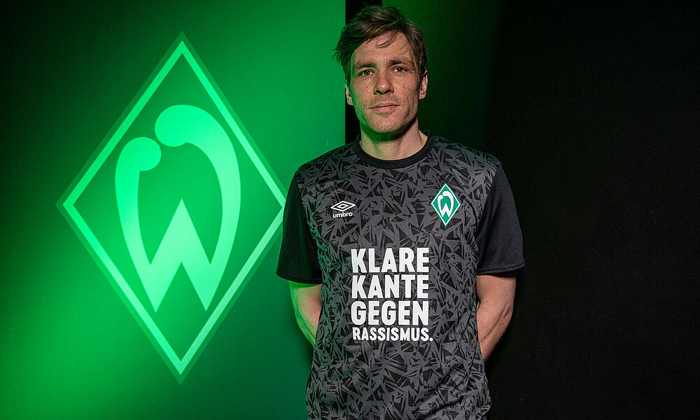 Clemens Fritz, Leiter Scouting und Profifußball beim SV Werder Bremen, präsentiert das neue Sondershirt, das den Slogan 